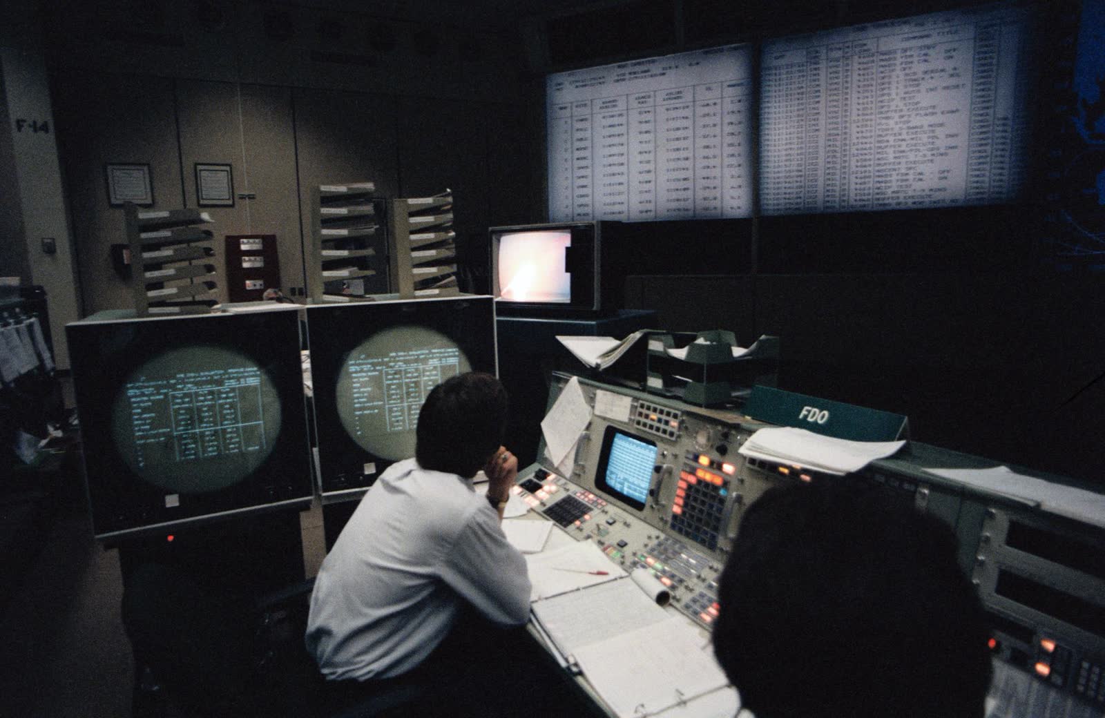 A control-room console lit by monitors