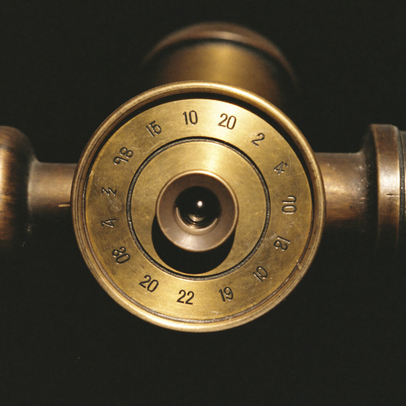 Close detail of an engraved brass setting circle on an old telescope mount, warm light raking across the numerals.