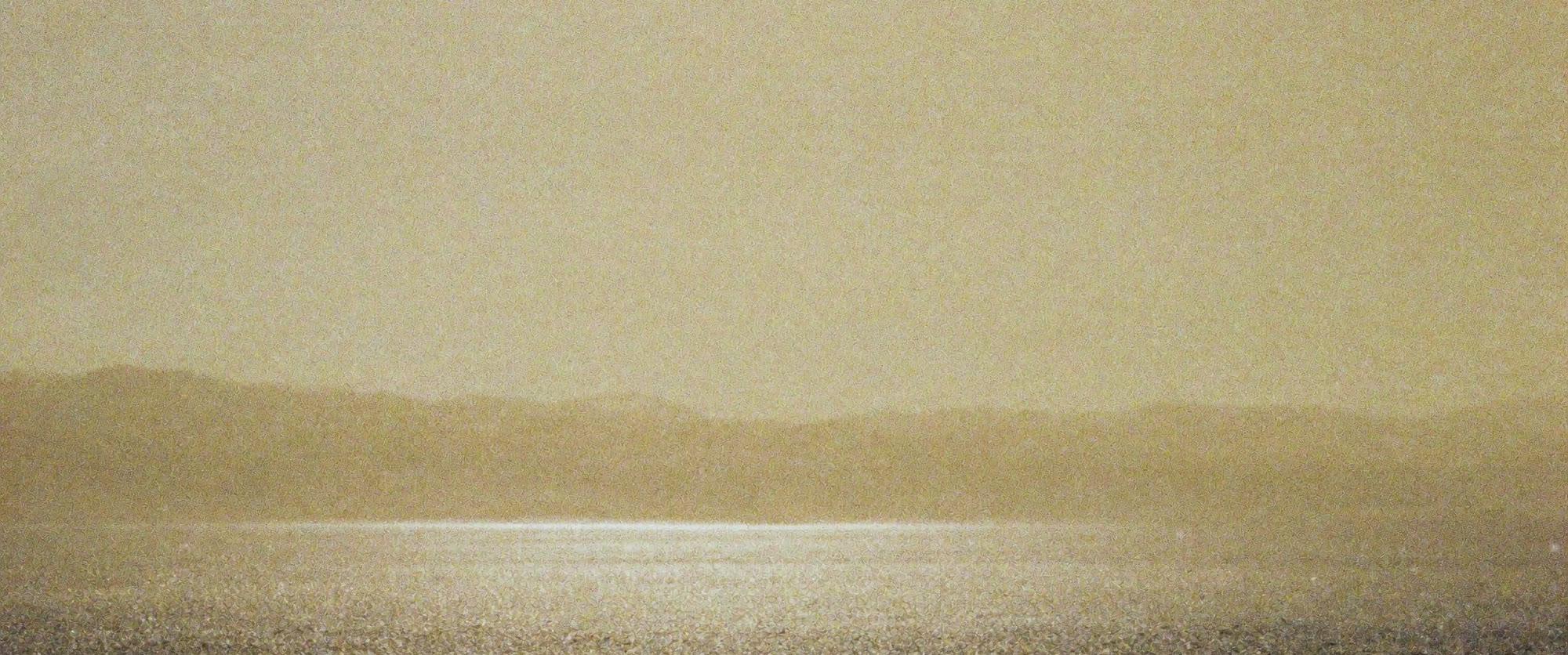 Heat haze shimmering over a vast empty gravel plain, distant hills dissolving into it.